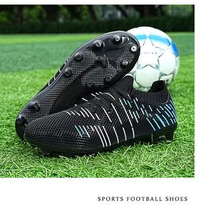 Detailed view of black football cleats with blue stripes and spiked soles on grass
