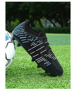 Close-up side view of professional black soccer cleats with blue stripes on grass field
