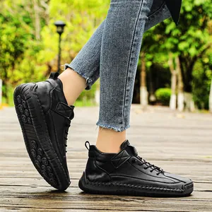 Detailed view of black mid-top men's boots with hand-stitched seams on a wooden path.