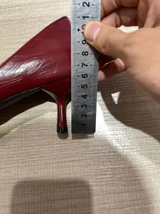 Detalle de zapato de tacón burdeos con punta fina y regla midiendo la altura del tacón