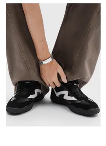 Close-up view of black racing sneakers with 7cm height increase and wavy white logo