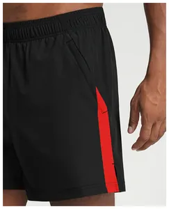 Detail of black athletic shorts featuring a vibrant red side stripe and functional pocket.