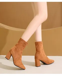 Nahaufnahme von braunen Wildleder-Stiefeletten mit Blockabsatz an einem Modell getragen
