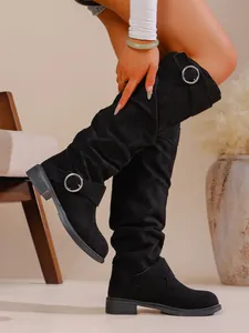 Detailansicht der schwarzen Wildleder-Slouch-Boots mit silbernen Metallschnallen.