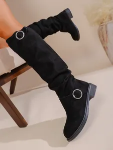 Detailansicht schwarzer Overknees aus Wildleder mit modischen silbernen Schnallen.