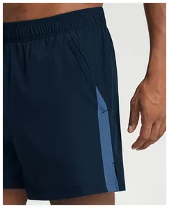 Close-up detail of men's breathable quick-dry sports shorts with blue patchwork side panel.