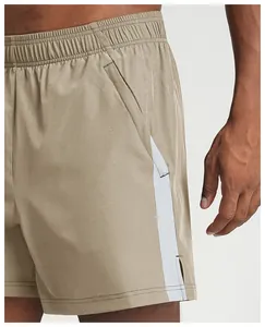 Close-up detail of khaki quick-dry athletic shorts with white side panels and pockets.