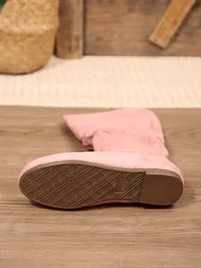 Detailansicht der rutschfesten braunen Gummisohle eines rosa Wildleder-Stiefels.