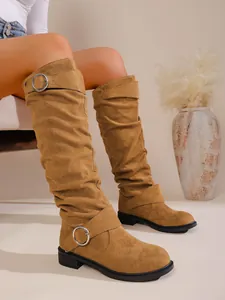 Detailansicht brauner Wildleder-Schlupfstiefel mit dekorativen silbernen Metallschnallen