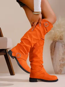 Detailansicht der orangefarbenen Wildlederstiefel mit Blockabsatz und Schnallen.