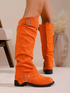 Nahaufnahme von hellorangen Wildleder-Slouch-Boots mit Schnallendetails