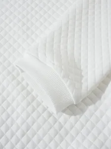 Détail d'un sweat-shirt blanc à motif de losanges matelassés avec poignet élastique côtelé.