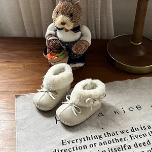Detailansicht gemütlicher cremefarbener Babystiefel mit Kunstfellfutter und Schleifen.