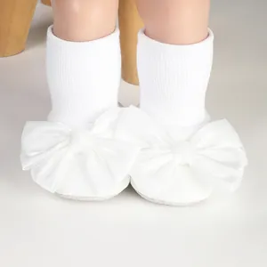 Detailed view of white baby floor socks featuring a large decorative satin bow detail