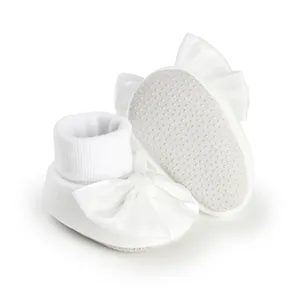 Detailed view of white baby socks featuring a large satin bow and anti-slip sole dots.