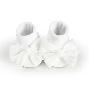 Detailed view of white baby floor socks with large elegant satin bow decoration