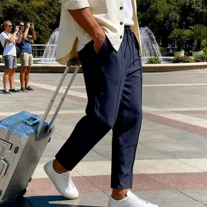 Pantaloni casual blu navy da uomo con una valigia in una piazza soleggiata all'aperto