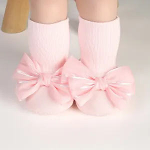 Close-up detail of soft pink baby non-slip floor socks featuring large decorative satin bows