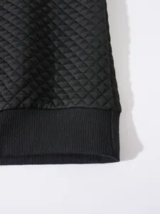 Détail rapproché d'un sweat-shirt noir en maille gaufrée avec ourlet côtelé et losanges