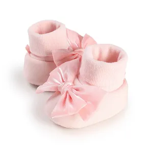 Close-up of soft pink baby floor shoes with large decorative satin bows and ribbed cuffs