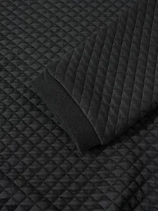 Gros plan sur la texture gaufrée et le poignet côtelé du sweat-shirt noir matelassé