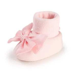 Detailed view of soft pink baby walk socks adorned with a large decorative satin bow
