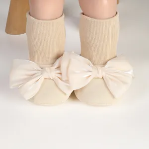Close-up detail of infant anti-slip floor socks featuring large cream satin bows