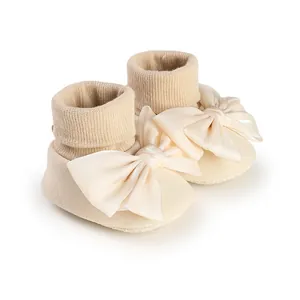 Close-up view of cream-colored baby floor socks with an elegant satin bow design