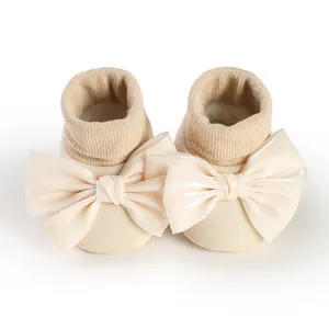 Close-up detail of beige baby floor socks featuring large elegant decorative satin bowknots