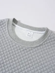 Détail de la texture et de l'étiquette d'un sweat-shirt gris en maille gaufrée