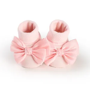 Detailed macro view of pink baby floor socks featuring oversized satin bows and ribbed cuffs