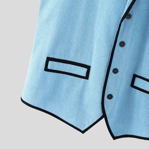 Detail einer hellblauen Cordweste für Herren mit schwarzen Kontrastpaspeln und Knöpfen