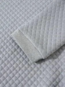 Vue rapprochée de la texture du sweat-shirt matelassé gris avec détail de poignet côtelé