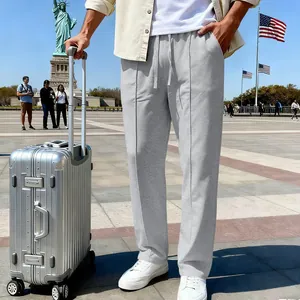 Pantaloni casual grigi larghi da uomo in una scena di viaggio con valigia argentata