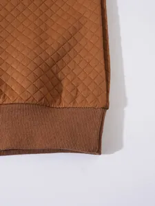 Gros plan du tissu matelassé marron et de l'ourlet côtelé d'un sweat-shirt décontracté.