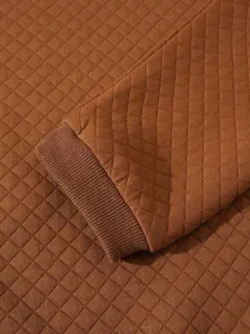 Détail rapproché d'un sweat-shirt matelassé marron avec poignet côtelé et motif en losange