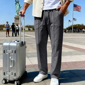 Pantaloni grigi casual a gamba larga da uomo con valigia argentata a Liberty Island