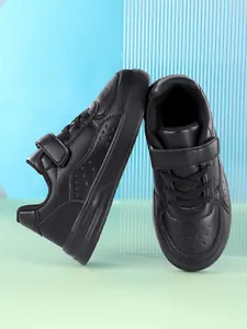 Professional close-up of black children's low-top skate shoes with Velcro straps.
