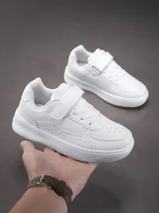 Close-up of white children's low-top sneakers with velcro strap and leather texture