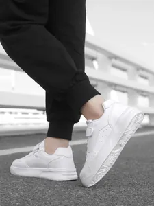 Detail shot of children's white low-top sneakers featuring convenient velcro straps.