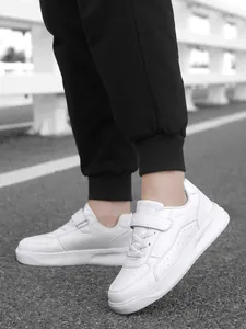 Detailed view of white children's sports shoes on feet on an outdoor pavement