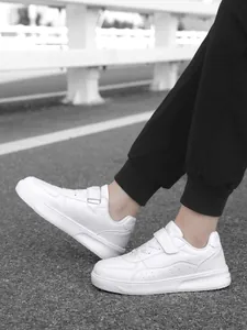 Detailed side view of white children's low-top sneakers featuring Velcro and laces