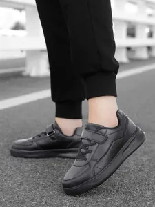 Close-up of black low-top children's sneakers with hook and loop closure for school