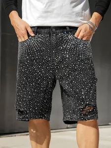 Close-up of men's black denim shorts with all-over rhinestone studs and ripped detail.
