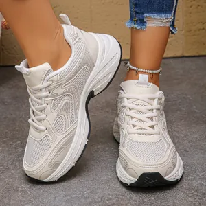 Close-up of stylish cream-white chunky dad shoes on feet with anklet accessory
