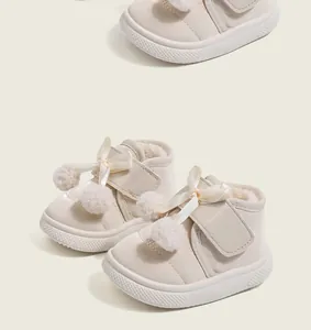 Detail shot of warm winter boots for toddlers with plush fur pom-poms and bow decor