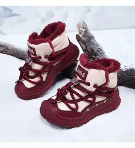 Detail of children's warm burgundy snow boots with thick fur lining and lace-up design