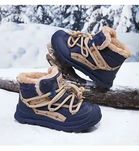 Detail view of navy blue kids' winter snow boots with warm faux fur lining in snow