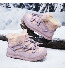 Macro view of warm pink fleece-lined kids winter snow boots in a outdoor snowy scene