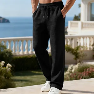 Detailansicht der schwarzen Waffelstrickhose für Herren in einer Küstenumgebung.